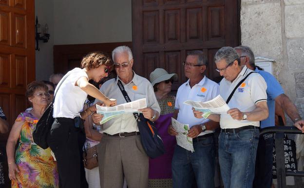 Varios visitantes consultan el plano de Cuéllar en la puerta de la oficina de Turismo.