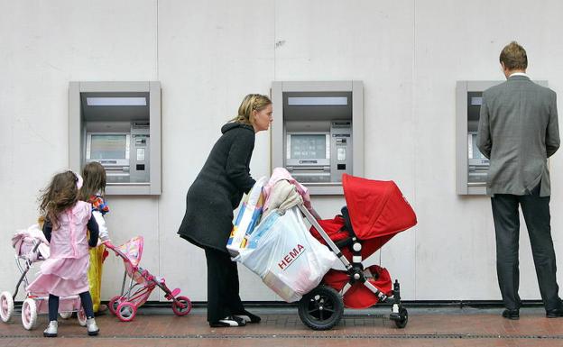 Algunos clientes utilizan los cajeros automáticos de una oficina bancaria./Koen van Weel-REUTERS
