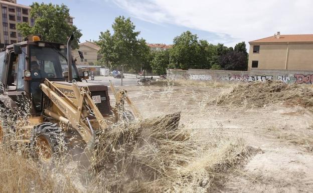 Una máquina excavadora limpia una parcela municipal./WORD
