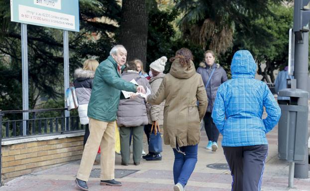Un miembro de la Plataforma entrega folletos en la puerta del Virgen de la Vega./MANUEL LAYA