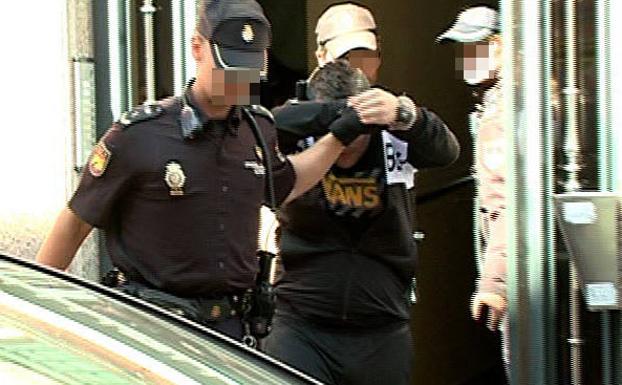 Dos policías conducen al sospechoso esposado después de registrar el domicio famliar de la Calle Cardenal Torquemada. /RTVCyL