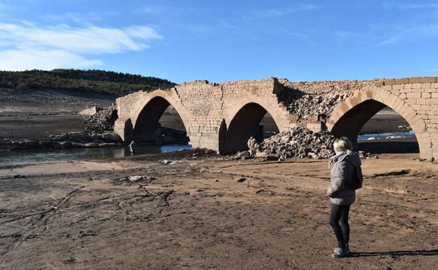 Una mujer observa los restos del puente de Villanueva del Río. /Nuria Estalayo