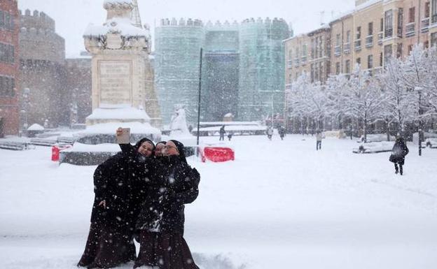 Tres monjas se hacen un selfi en el Mercado Grande de Ávila durante la nevada que cubre la ciudad.. Raúl Sanchidrián/