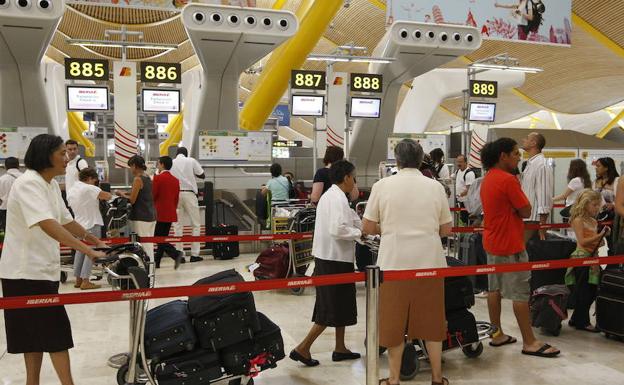 Pasajeros esperando con su equipaje en la T4 del aeropuerto de Barajas./Manuel H. de León/EFE