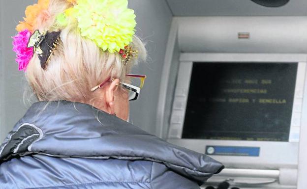 Uha personas mayor saca dinero de un cajero. /A. de Torre