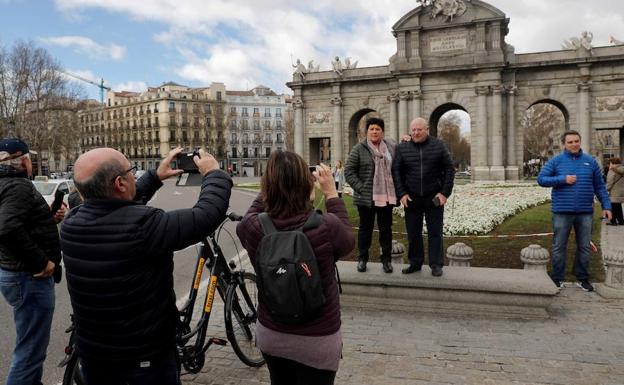 Varios turistas se fotografían ante la Puerta de Alcalá, en Madrid. /EFE