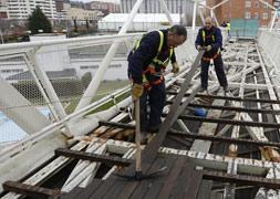 Los operarios desmontan las listas de madera del suelo de la pasarela / G. Villamil/