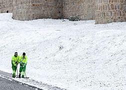 Dos operarios limpian de nieve una de las aceras que circundan la muralla de Ávila. RAÚL SANTIDRIÁN/