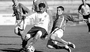 Un jugador del Unami trata de superar la entrada de un contrario en La Albuera. / ANTONIO DE TORRE/
