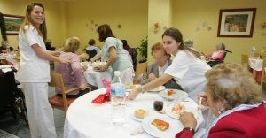 Varias trabajadoras de El Encinar del Rey sirven la cena de Nochebuena a varias personas mayores en unas pasadas navidades. :: HENAR SASTRE/