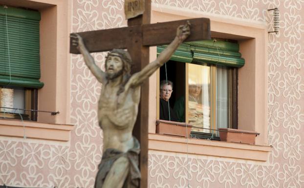 Unos vecinos observan el paso del Santísimo Cristo por su calle. /Óscar Costa